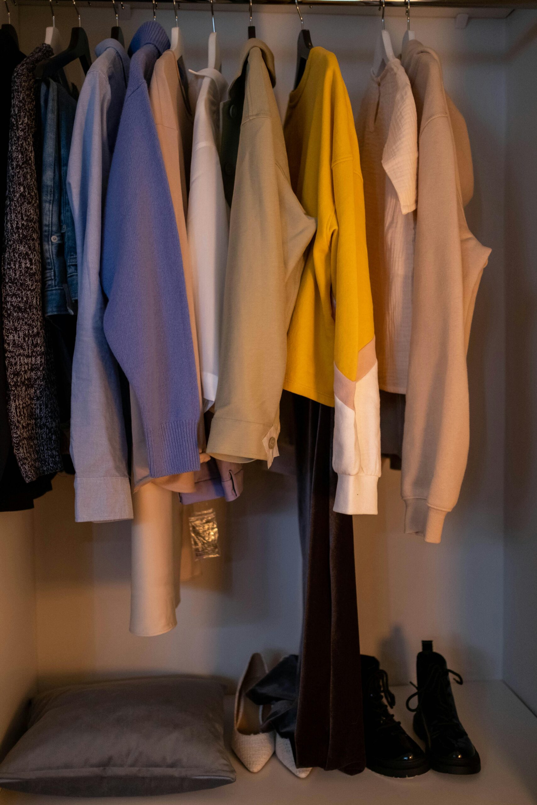 Guardaroba con capi di abbigliamento appesi in diversi colori e tonalità