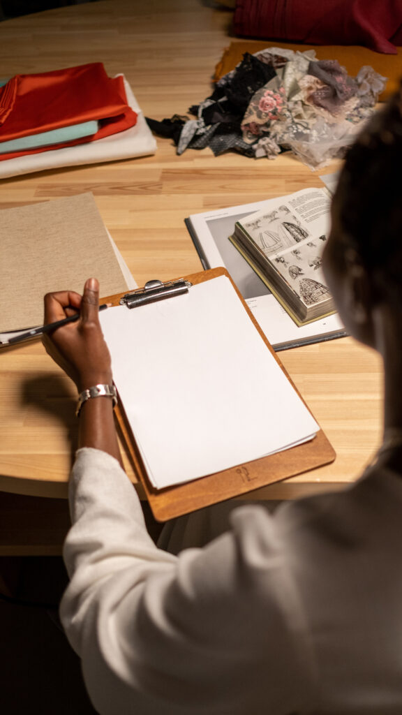 Persona al lavoro su un progetto di personal brand con quaderno, materiali e campioni visivi